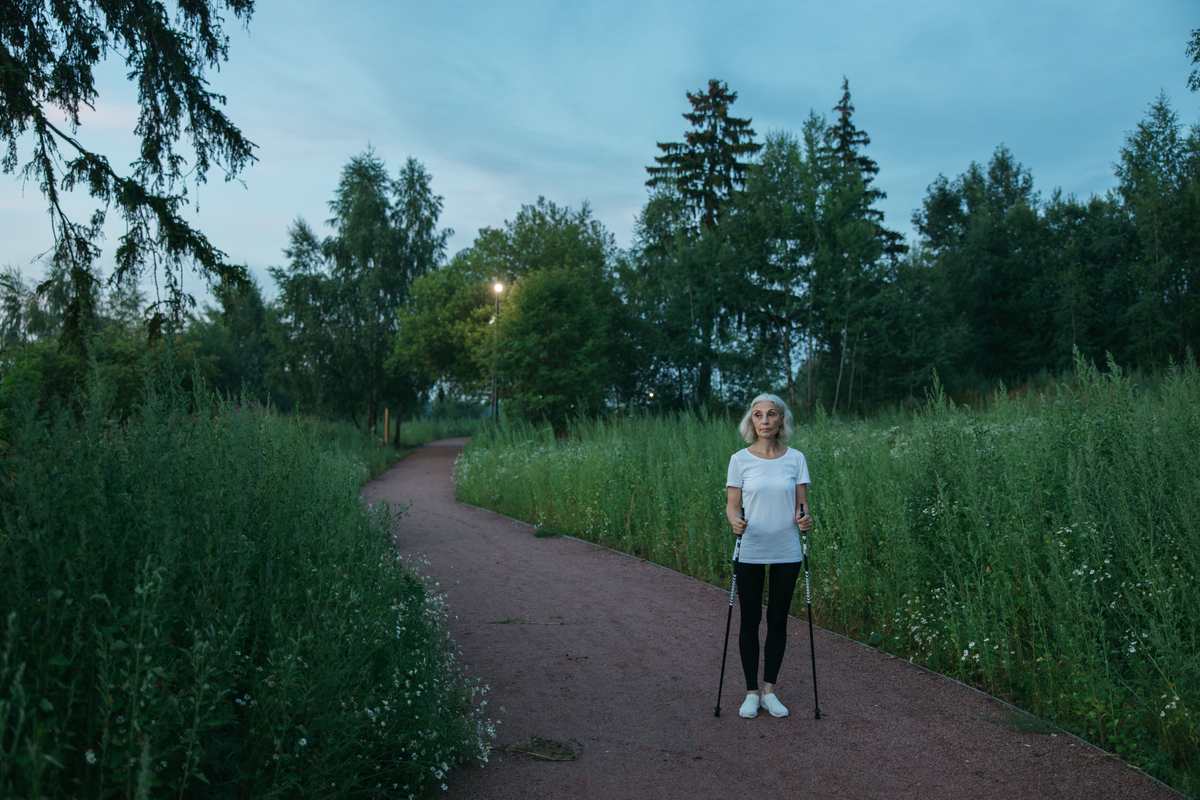Woman standing outdoors with walking poles