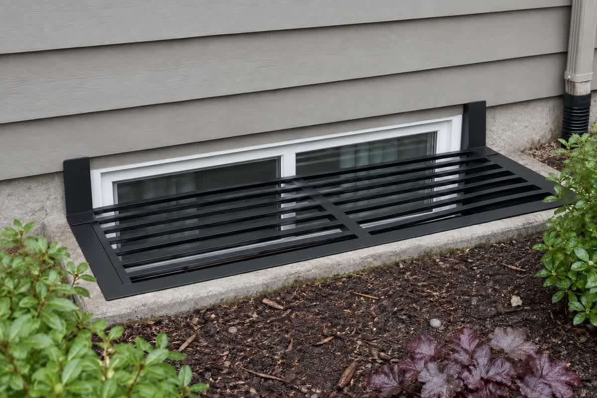 Black metal grille positioned outside a basement window beside gray siding